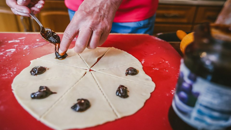 Každou placku rozkrájíme na výseče - na osm dílů. Na vnější kraj každé výseče položíme vrchovatou čajovou lžičku povidel