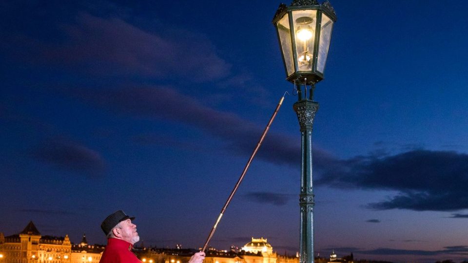 Lampář v období adventu rozsvěcuje plynové lampy na Karlově mostě