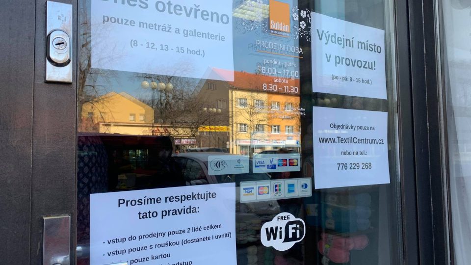 Upozornění na vchodu do prodejny s textilem v Kroměříži